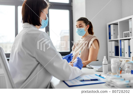 female doctor with syringe vaccinating patient female doctor with syringe vaccinating patient 80728202