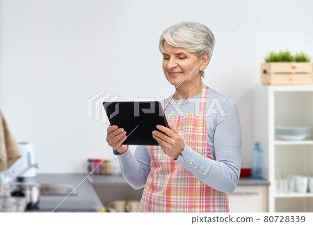 smiling senior woman with tablet pc at kitchen 80728339