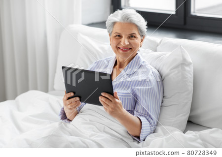 senior woman with tablet pc in bed at home bedroom senior woman with tablet pc in bed at home bedroom 80728349