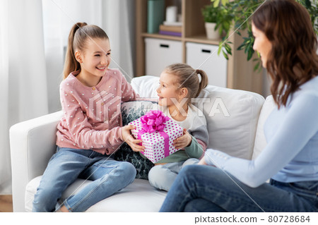 daughters giving present to happy mother 80728684