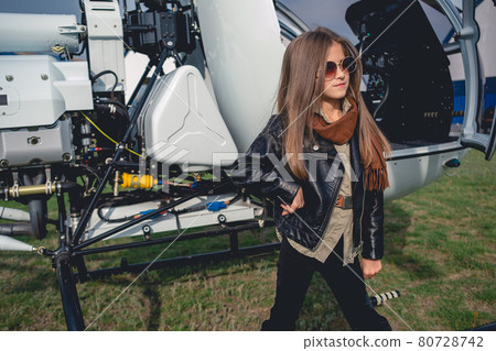 Confident tween girl in sunglasses standing near open helicopter Confident tween girl in sunglasses standing near open helicopter 80728742