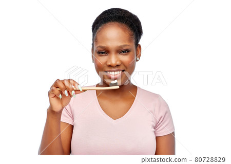 smiling woman with toothpaste on wooden toothbrush smiling woman with toothpaste on wooden toothbrush 80728829