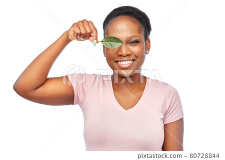 smiling african american woman holding green leaf smiling african american woman holding green leaf 80728844