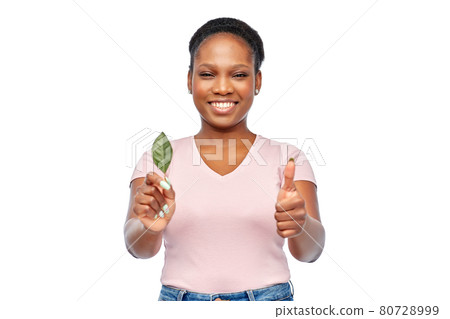 smiling african american woman holding green leaf 80728999