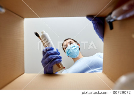 woman in mask unpacking parcel box with cosmetics woman in mask unpacking parcel box with cosmetics 80729072