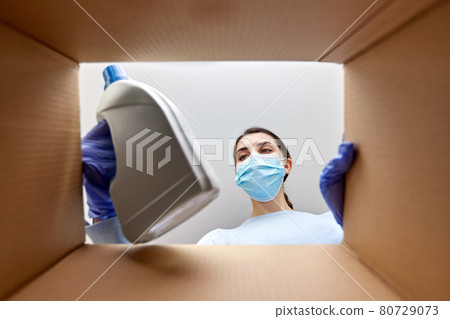 woman in mask taking cleaning supplies from box woman in mask taking cleaning supplies from box 80729073