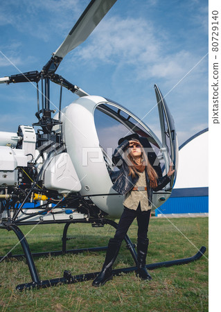 Preteen girl in sunglasses looking at sky near helicopter 80729140