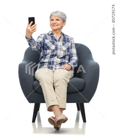 smiling senior woman sitting in modern armchair smiling senior woman sitting in modern armchair 80729174