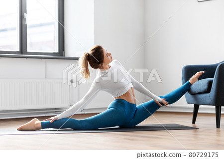 young woman stretching and doing yoga at home 80729175