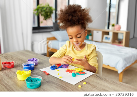little girl with modeling clay playing at home 80729316