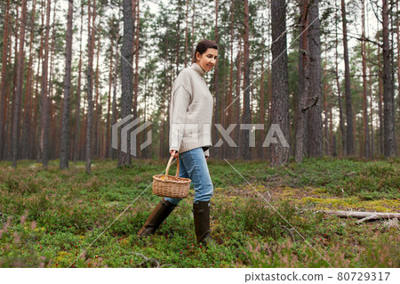 woman with basket picking mushrooms in forest 80729317