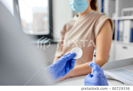 female doctor with syringe vaccinating patient 80729336