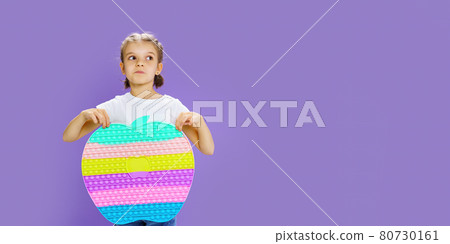 Kid holding huge apple anti stress bubble. motor skills. pop it fun. child holding color popit fidget 80730161