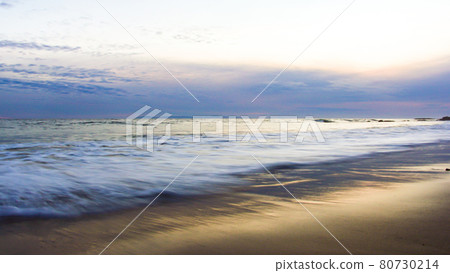A beach with white waves in the setting sun 80730214