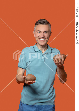 Man holding out small coconuts in his palms 80730699