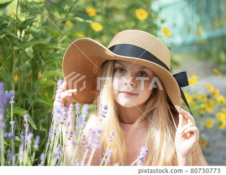 Little girl in a straw hat surrounded by lavender flowers 80730773