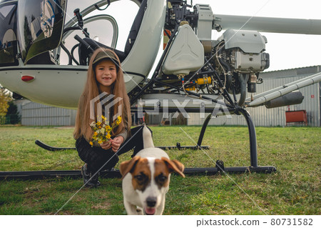 Happy preteen girl playing with puppy near helicopter 80731582