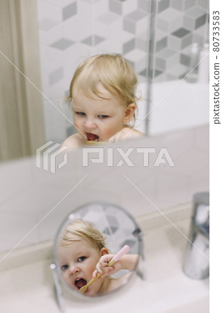 reflection in the mirror of a little funny girl brushing her teeth reflection in the mirror of a little funny girl brushing her teeth 80733583