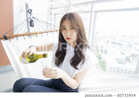 Woman drinking alcohol in a hammock 80733954