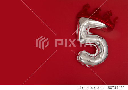 Balloon 5 in crown on dark red background flat lay Balloon 5 in crown on dark red background flat lay 80734421