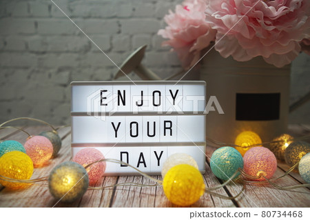 Enjoy Your Day text on lightbox on wooden background Enjoy Your Day text on lightbox on wooden background 80734468