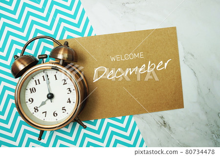 Welcome December typography text on paper card with alarm clock on marble background 80734478