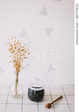 Dry black tea in glass jar and honey spindle on kitchen background. Hot drink in cold period 80734620