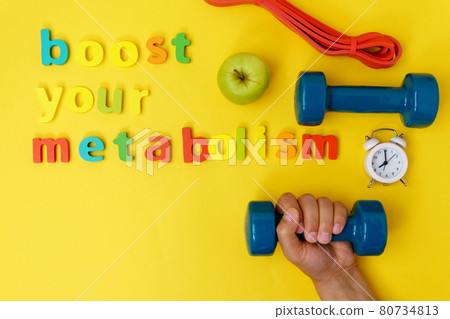 Boost Your Metabolism, sport and dumbbell. Top view. Yellow background Boost Your Metabolism, sport and dumbbell. Top view. Yellow background 80734813