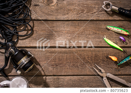 Fishing tackle - fishing spinning, fishing line, hooks and lures on wooden background. Fishing tackle - fishing spinning, fishing line, hooks and lures on wooden background. 80735623