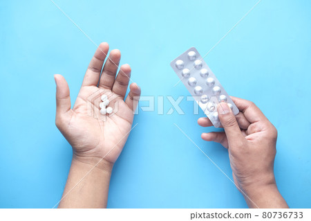 man's hand with medical pills and blister pack on blue  80736733