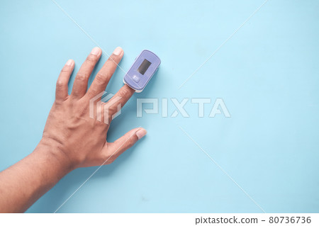 close up of man hand using pulse oximeter on blue background  80736736
