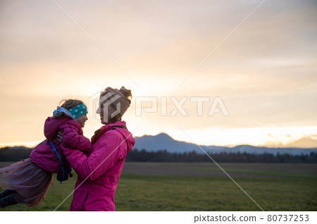 Happy young mother having fun with her toddler daughter outside in a meadow Happy young mother having fun with her toddler daughter outside in a meadow 80737253
