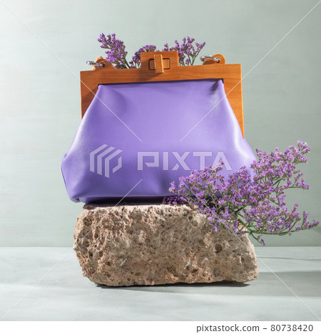 Natural rough gray stone podium with purple female handbag flowers 80738420