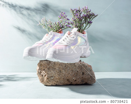 White sneakers with purple flowers on turquoise on stone podium 80738421
