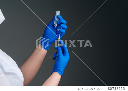 Close-up studio shot of unrecognizable nurse in white gloves holding and filling up vaccine to syringe on black isolated background. Close-up studio shot of unrecognizable nurse in white gloves holding and filling up vaccine to syringe on black isolated background. 80738633