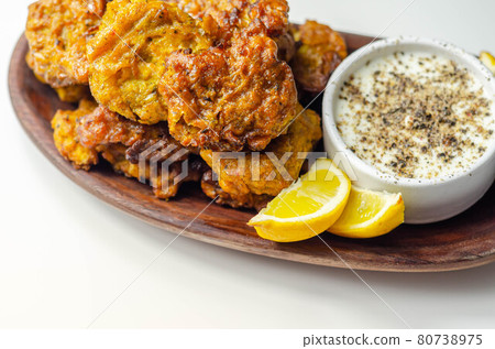 Delicious onion bhaji fritters served on wooden plate with white dip Delicious onion bhaji fritters served on wooden plate with white dip 80738975