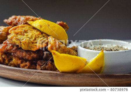 Delicious onion bhaji fritters served on wooden plate with white dip 80738976