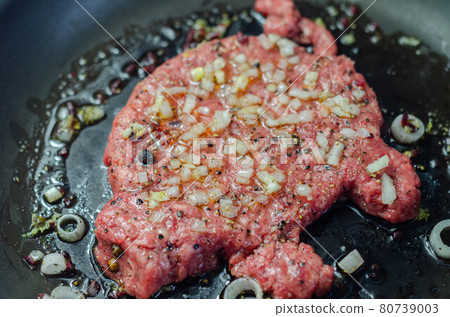 Minced meat with fresh spring onions and spices in the shape of a pig, fried in a pan, a creatively prepared burger in an interesting shape Minced meat with fresh spring onions and spices in the shape of a pig, fried in a pan, a creatively prepared burger in an interesting shape 80739003