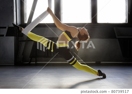 Woman doing split aerial yoga pose hanging in hammock in class 80739517