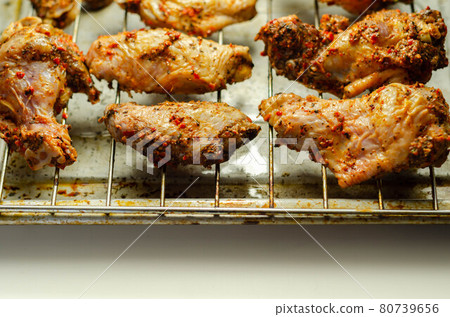 Raw chicken wings with a rendang style rub made with chilli and garlic on the grill tray Raw chicken wings with a rendang style rub made with chilli and garlic on the grill tray 80739656