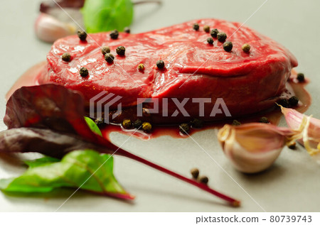 Raw beef sirloin steak with peppercorns and garlic prepared for frying Raw beef sirloin steak with peppercorns and garlic prepared for frying 80739743