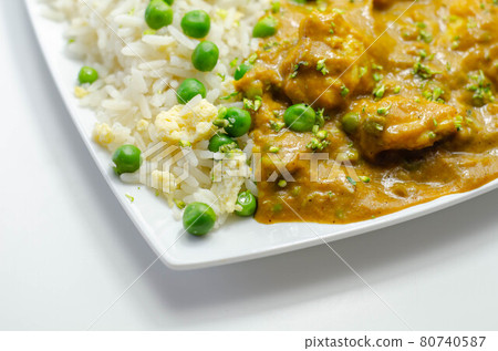 Chicken curry with egg fried rice, chicken breast pieces in a mildly spiced coconut curry sauce with fried rice with peas and egg 80740587