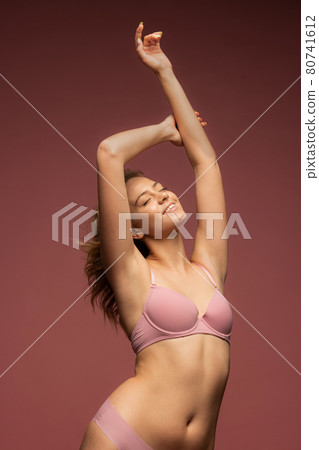 Young beautiful woman in pink underwear on brown background Young beautiful woman in pink underwear on brown background 80741612