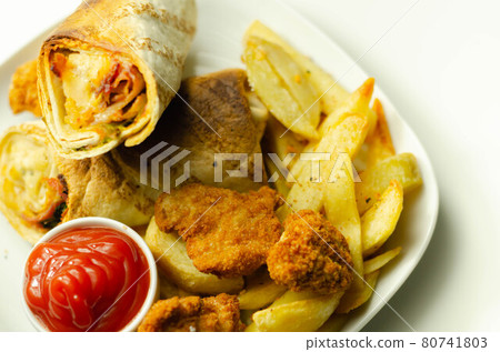 Tortilla wrap with chicken and beechwood smoked bacon served with chicken nuggets and chips on the white plate 80741803