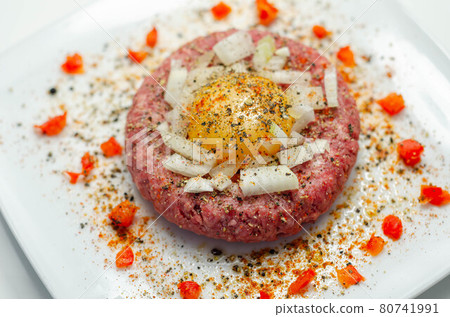 Beef steak tartare with raw egg yolk and onion with tomato Beef steak tartare with raw egg yolk and onion with tomato 80741991