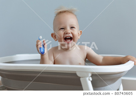 laughing small child rushes his teeth while sitting in the bathroom 80743605