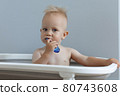 A small child rushes his teeth while sitting in the bathroom 80743608