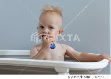 A small child rushes his teeth while sitting in the bathroom 80743608