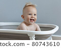 little boy is sitting in a bath and laughing 80743610