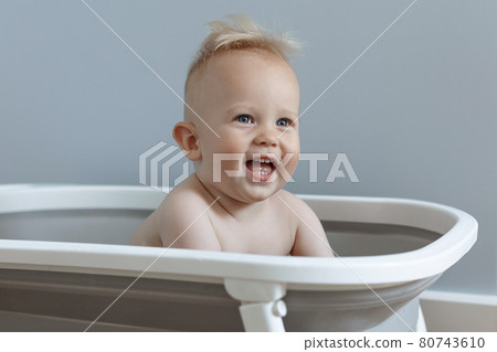 little boy is sitting in a bath and laughing 80743610